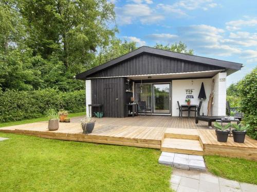 a small house with a wooden deck in a yard at 5 person holiday home in Vinderup-By Traum in Vinderup