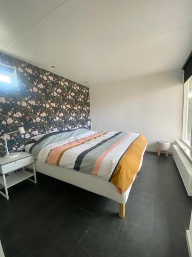 a bedroom with a bed with a floral wall at Bungalow near beach with large private garden - not for companies in Ouddorp