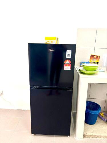 a black refrigerator in a kitchen next to a counter at Rizku Homestay Port Dickson 4 Bedroom 4 Bathroom in Pasir Panjang
