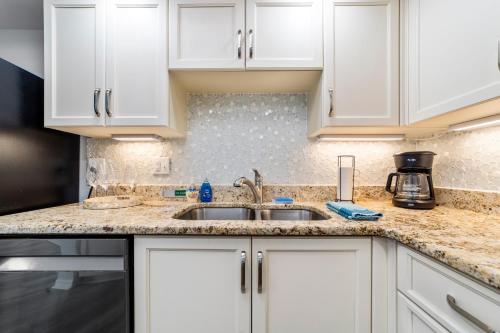 a kitchen with white cabinets and a sink at On the Beach-2/Br 2/Bath, 26th floor! Spectacular views of Ocean & River in Daytona Beach Shores