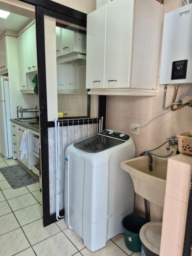 a small kitchen with a washer and a sink at Caioba Apto Confortavel in Matinhos