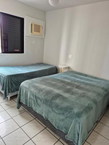 two beds in a room with a window at Caioba Apto Confortavel in Matinhos