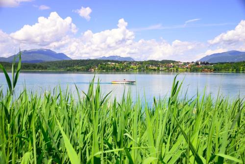 a boat on a lake with mountains in the background at Apart of me Ferienhaus Faaker See in Egg am Faaker See