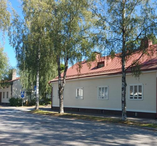 a white building with a red roof and trees at Apartment Lintu in Mikkeli