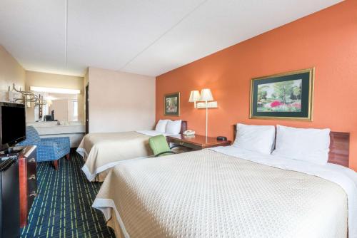 a hotel room with two beds and a flat screen tv at Days Inn by Wyndham Pittsburgh-Harmarville in Harmarville