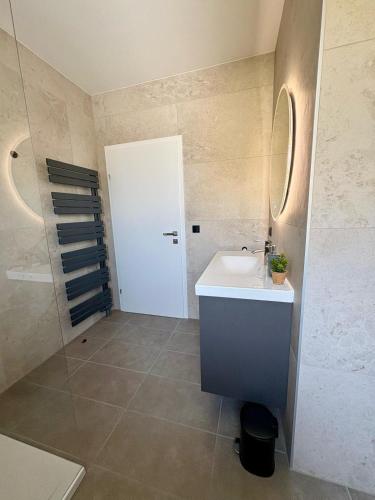 a bathroom with a white sink and a shower at Fresh Apartment Upstairs & Free Parking in Graz