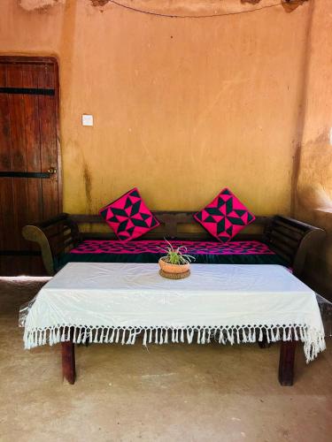 a bed with pink and purple pillows on it at Yala Beddegama Eco in Kataragama