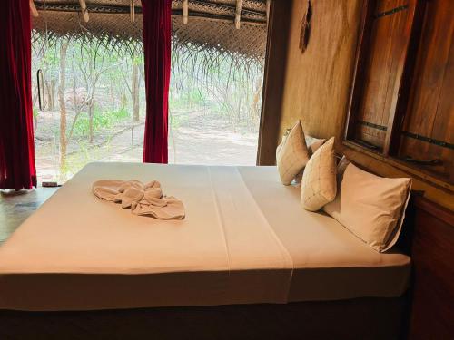 a bed with two flip flops on it with a window at Yala Beddegama Eco in Kataragama