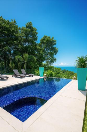 a swimming pool with chairs and the ocean in the background at Blue Samui Ocean Villa - 3 Large Ensuite Bedrooms - Private Pool, Jacuzzi Villa & Car with driver - Near Four Seasons - Ocean & Mountains Views in Nathon Bay