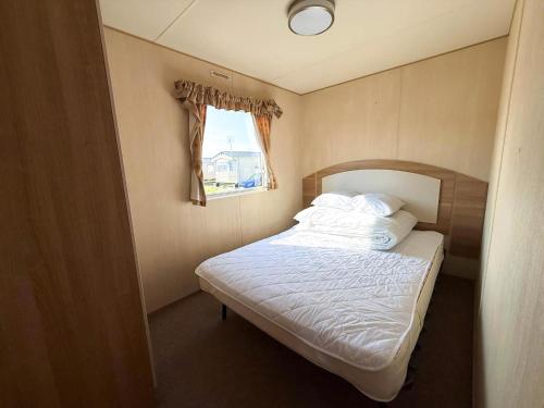 a small bed in a small room with a window at Superb 8 Berth Caravan At St Osyth Beach Holiday Park, Essex Ref 28010Mv in Clacton-on-Sea