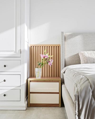 a bed with a night stand with a vase with flowers on it at Lakeview Park Villas - Every Duplex with Private Pool in Ho Chi Minh City