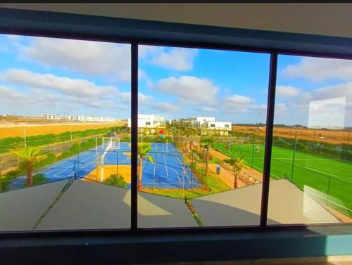 a view of a tennis court from a window at Appartement vue piscine - Pour Famille - Blue Beach SIDI RAHAL in Sidi Rahal