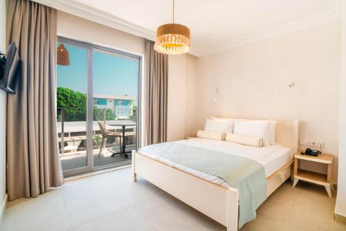 a white bedroom with a bed and a balcony at Victoria Princess Hotel in Side