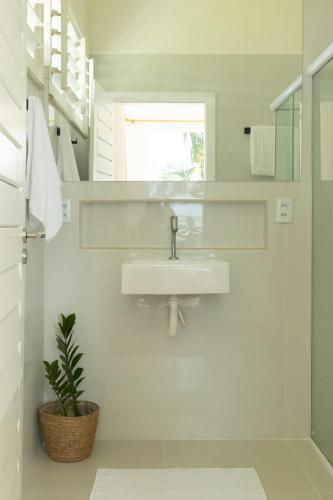 a white bathroom with a sink and a plant at Soulkite House Brazil in Itarema