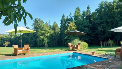 a swimming pool with chairs and umbrellas at Gästehaus Cube am Forsthaus in Hausbach