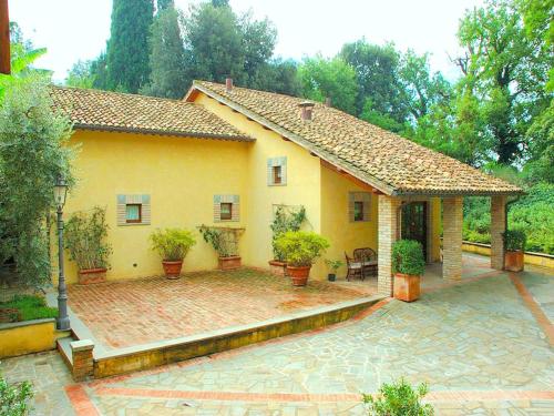 a yellow house with potted plants on a patio at Apartment in Perugia with Pool & Terrace in Perugia