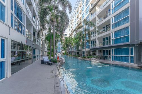 einem Pool in der Mitte eines Gebäudes mit Palmen in der Unterkunft Vanko International Hotel Pattaya Central in Pattaya
