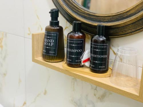 a shelf with three bottles of soap and a mirror at Rezidenca SHOPI Apartments in Elbasan