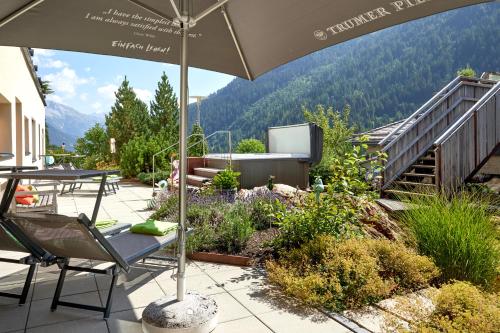 a patio with an umbrella and a table and chairs at Der Waldhof - Unique - A hidden gem in Sankt Anton am Arlberg
