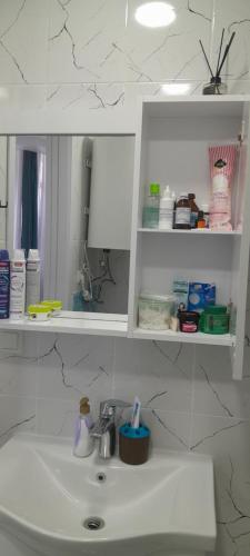 a bathroom sink with a white cabinet above it at Lovely Apartment in City Center in Batumi
