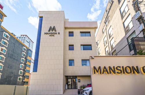 a tan building with a sign in front of it at Pohang Mansion 6 Hotel in Pohang