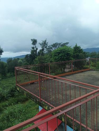 a red metal bridge over a field with trees at saraswati home stay in Pālampur