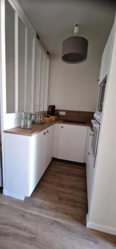 a kitchen with white cabinets and a wooden floor at STUDIO bord de mer in San-Nicolao
