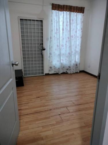 an empty room with a wooden floor and curtains at Taman Cerah Homestay in Kota Kinabalu