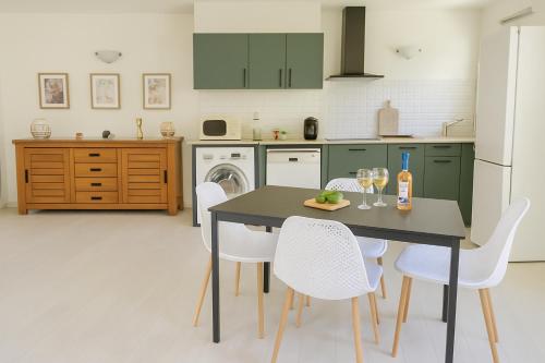a kitchen with green cabinets and a table and chairs at Villa Ohna - Gîte Romantique avec Spa Privé in Vals-les-Bains