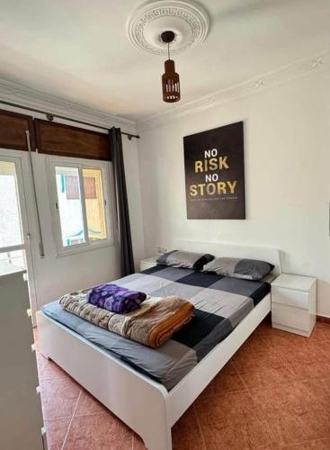 a bedroom with a bed with a no risk top story sign on the wall at Apparemment familiale in Martil