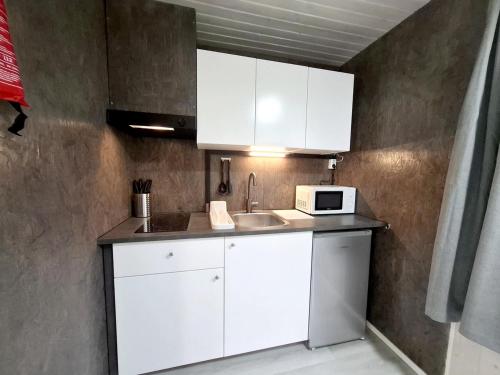 a kitchen with white cabinets and a microwave at WOLF Lakeside Cabins Lapland in Rovaniemi