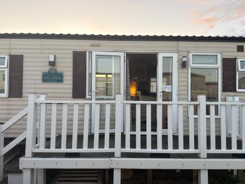 a mobile home with a white porch and a door at Caravan by the sea in Gristhorpe
