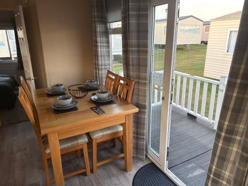 a dining room with a table and chairs and a balcony at Caravan by the sea in Gristhorpe