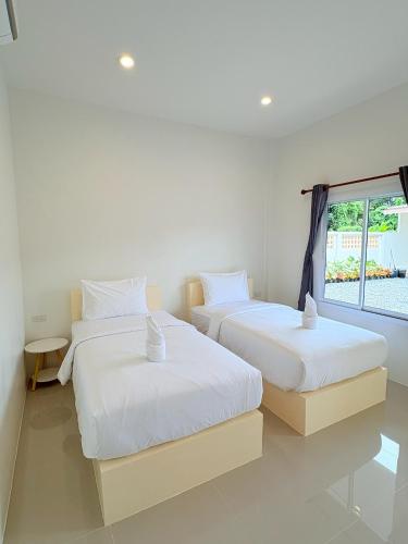 two beds in a room with a window at Cozy House Chanthaburi in Chanthaburi