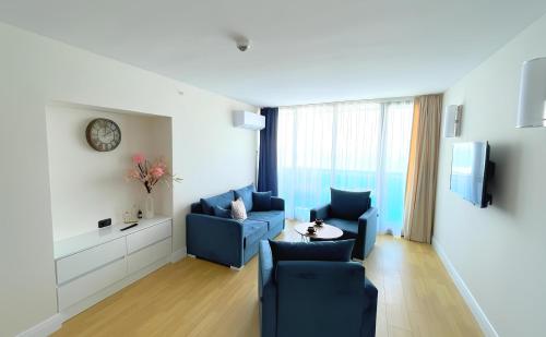a living room with two blue chairs and a table at PANORAMA LUXURY ORBI CITY Aparthotel in Batumi