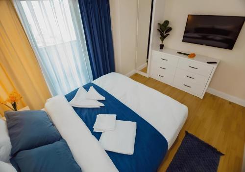 a bedroom with a blue and white bed and a tv at PANORAMA LUXURY ORBI CITY Aparthotel in Batumi