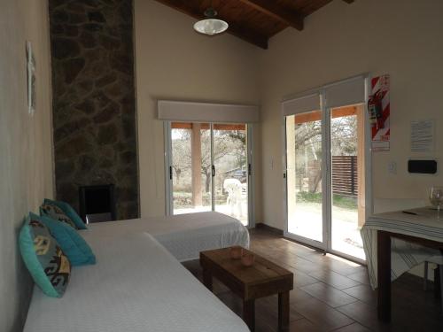 - une chambre avec 2 lits et une porte donnant sur une terrasse dans l'établissement Los Cantaros, à Santa Rosa de Calamuchita