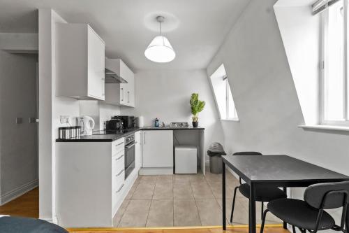 a kitchen with white cabinets and a table with chairs at Large Delux Studio - 26 in Leicester
