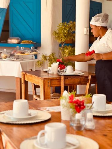 a man preparing food at a table in a restaurant at Pousada Ilha do Vento in São Miguel do Gostoso