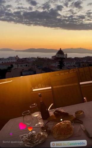 a table with a bottle of wine and a plate of food at B&B Su Canistreddu in Alghero