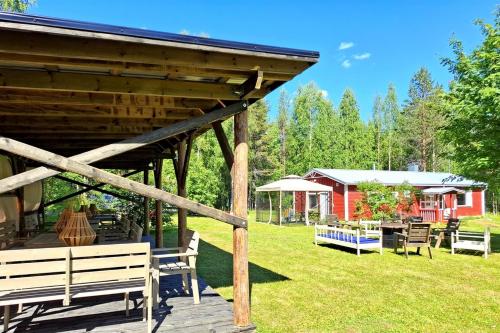 a pavilion with benches and tables and a red building at WOLF Lakeside Cabins Lapland in Rovaniemi
