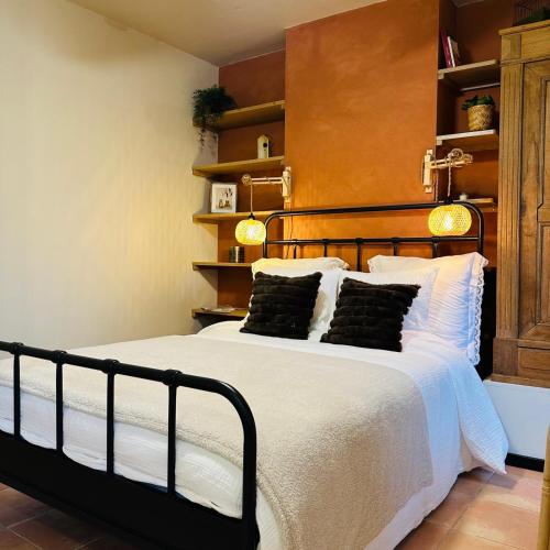 a bedroom with a bed with white sheets and black pillows at OrigiNell - EmotioNell in Ouffet