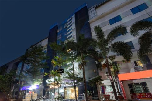a tall building with palm trees in front of it at Super Townhouse Lotus Grand in Hyderabad