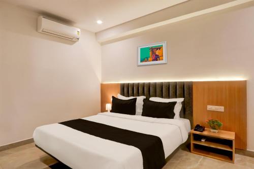 a bedroom with a large white bed with black pillows at Super Townhouse Lotus Grand in Hyderabad