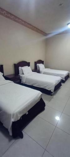 a row of beds in a room with white walls at ايواء قمر الشرق للشقق المخدومة in Dammam