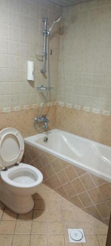 a bathroom with a toilet and a bath tub with at ايواء قمر الشرق للشقق المخدومة in Dammam