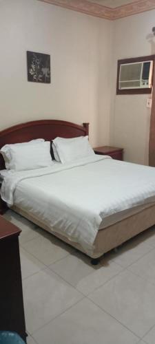 a bedroom with a large bed with white sheets and pillows at ايواء قمر الشرق للشقق المخدومة in Dammam