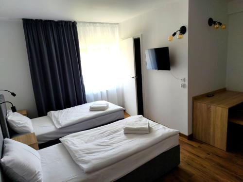 a hotel room with two beds and a television at Villa Polonia in Jelenia Góra
