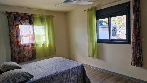 a bedroom with a bed and a window with green curtains at Bel horizon M&J location voiture sur demande in Saint-Paul