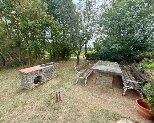 a bench and a table and a stone fireplace at Szaletli in Tihany